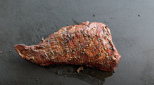 Perfectly grilled coffee-marinated tri-tip resting on the grill, uncut.