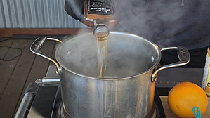 Pouring bourbon into a simmering pot to make a maple bourbon glaze for ham.