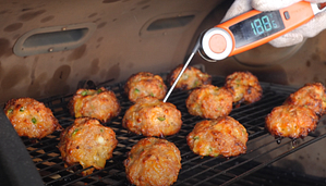 Checking the temperature of smoked sausage balls on a Z Grills pellet grill, showing perfect doneness.