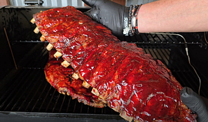 Ribs fully grilled and coated with BBQ sauce, displaying a shiny glaze.